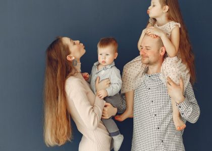 Portrait of a joyful family with parents and kids showing love and affection against a blue background.